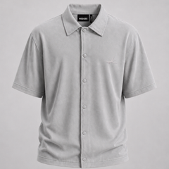 A light gray short-sleeve button-up shirt with a classic collar and a small embroidered logo on the left chest, displayed on a neutral gray background.