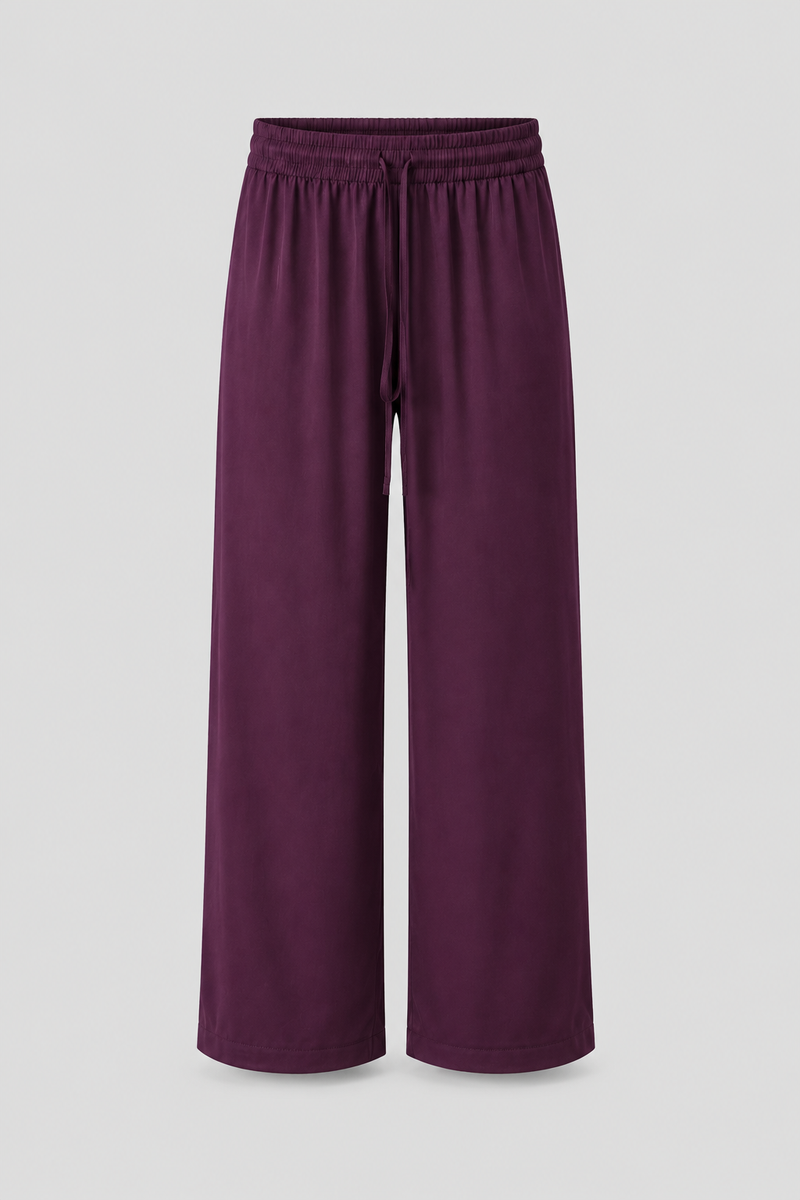 A pair of wide-leg lounge pants in a deep plum purple color, featuring an elastic waistband and drawstring, shown against a neutral light gray background.