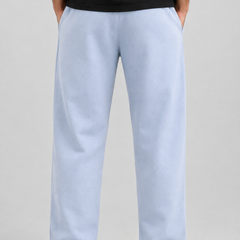 A person shown from the back wearing light blue wide-leg sweatpants, a black t-shirt, and white sneakers against a neutral gray studio background.