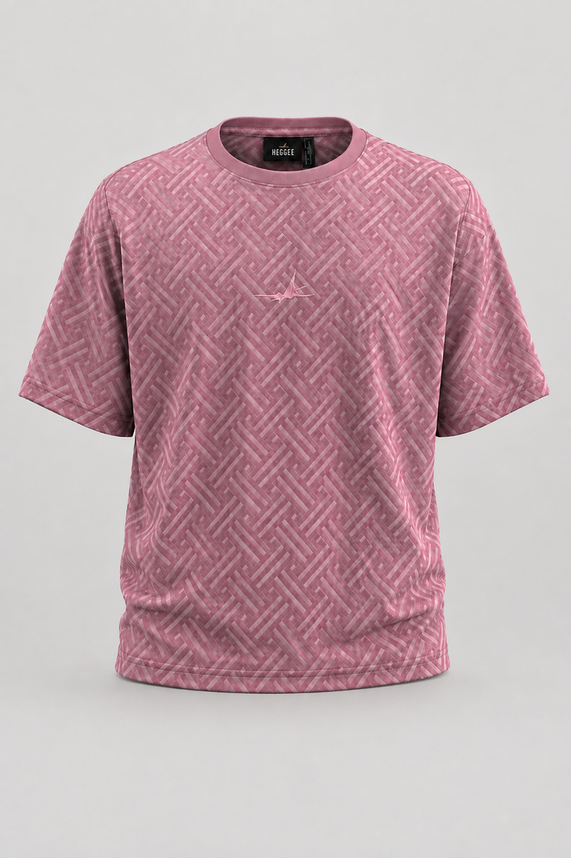 A pink short-sleeve crewneck t-shirt with a tonal geometric basketweave pattern and a small tonal logo on the left chest, displayed on a neutral light gray background.