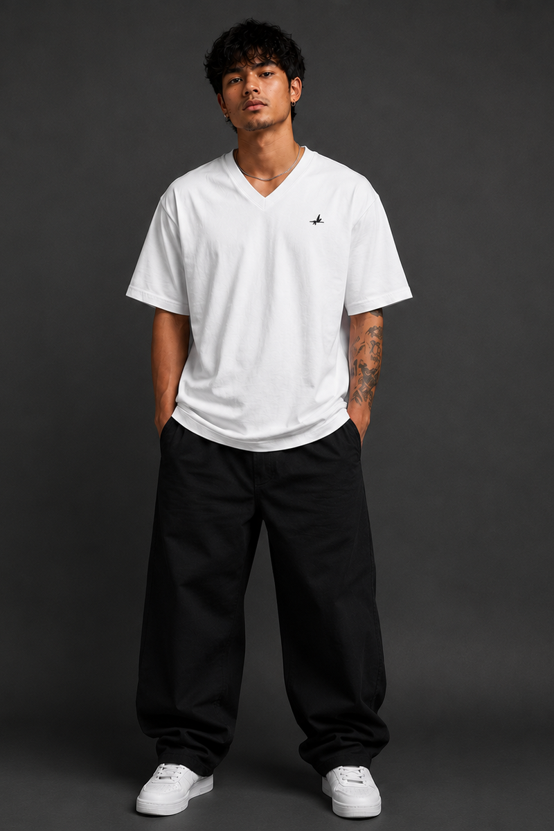 Person wearing a white t-shirt with a logo and black pants on a dark background