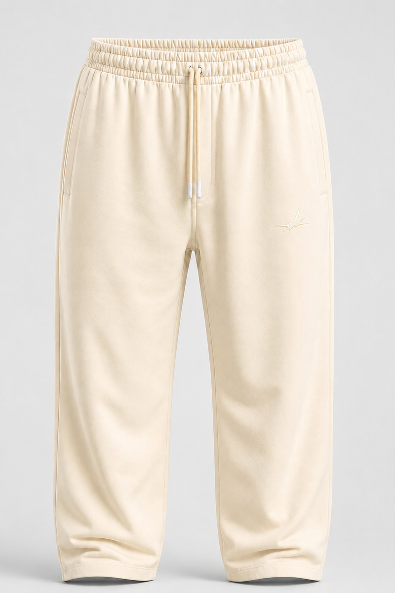 Cream-colored fleece sweatpants with an elastic waistband, drawstring, and a small embroidered logo on the left thigh, shown against a light gray background.