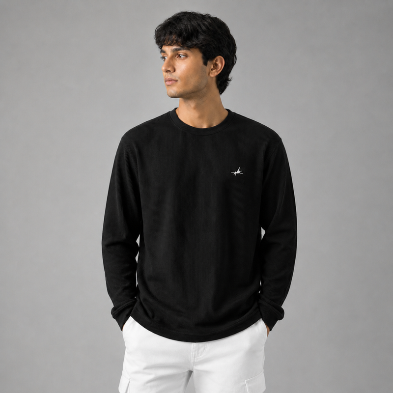Man wearing a black long-sleeve shirt with a small logo on a gray background