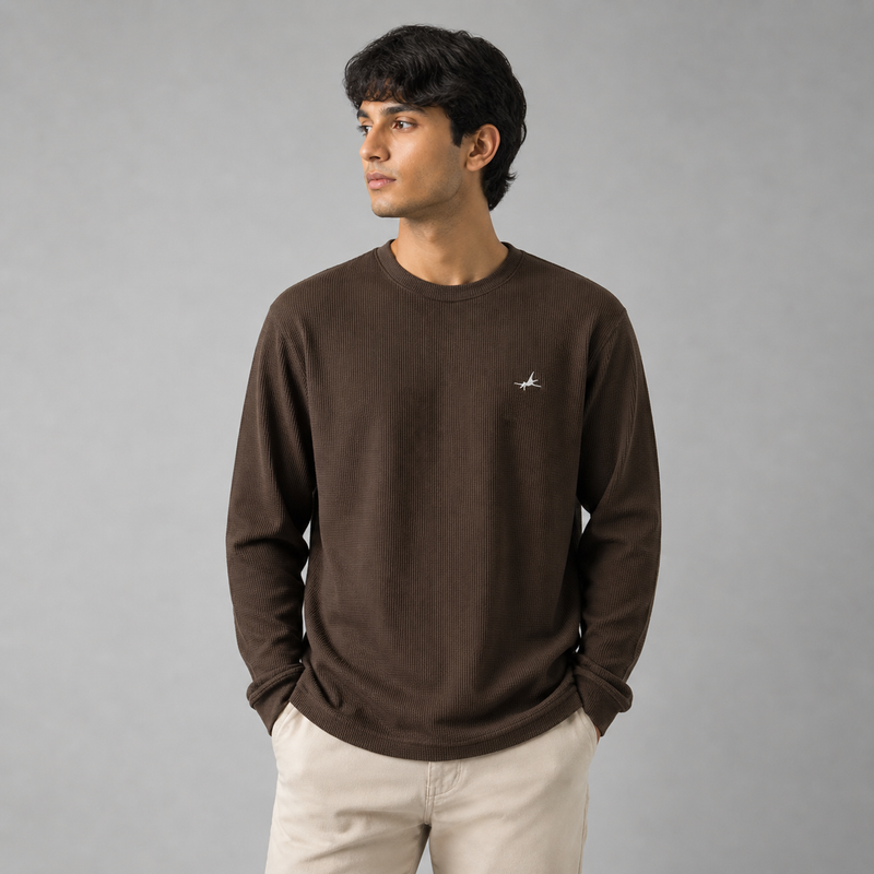 Man wearing a brown long-sleeve shirt with a small logo on a gray background