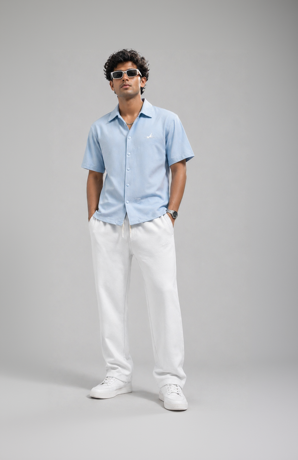 Man wearing a light blue shirt and white pants on a gray background with promotional text.