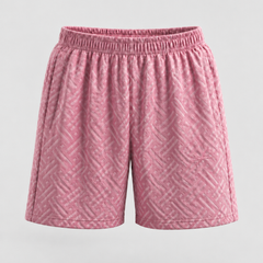 Pink athletic shorts with a textured geometric pattern and an elastic waistband, shown against a light gray background.