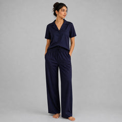 Woman wearing a navy pajama set against a gray background