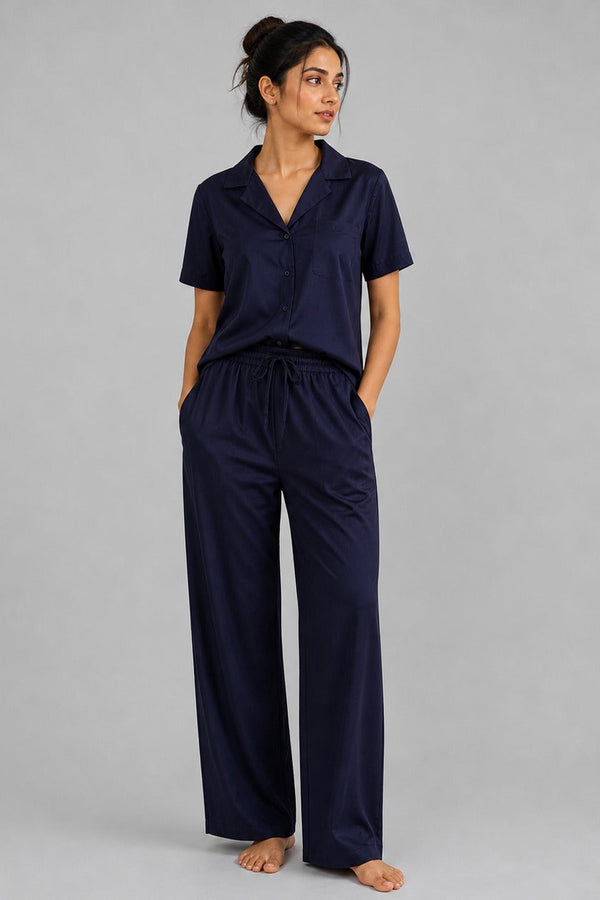 Woman wearing a navy pajama set against a gray background