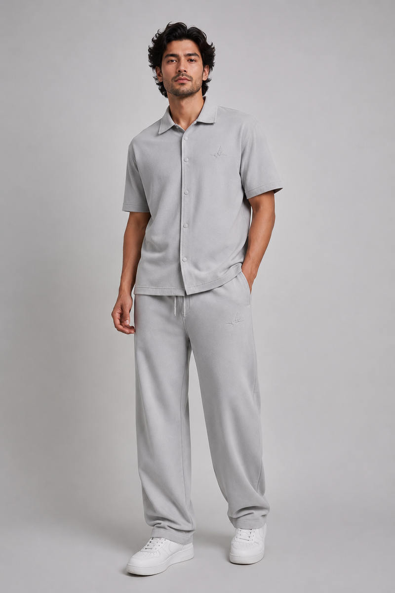 a man model wearing grey co-ord set with logo on a light grey studio background