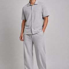 a man model wearing grey co-ord set with logo on a light grey studio background