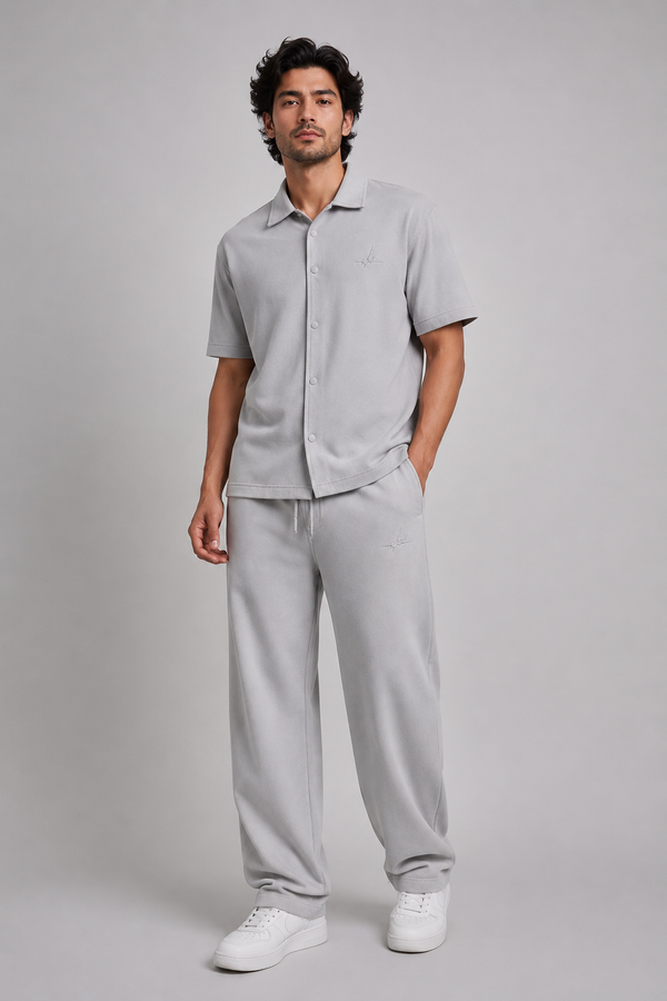 a man model wearing grey co-ord set with logo on a light grey studio background